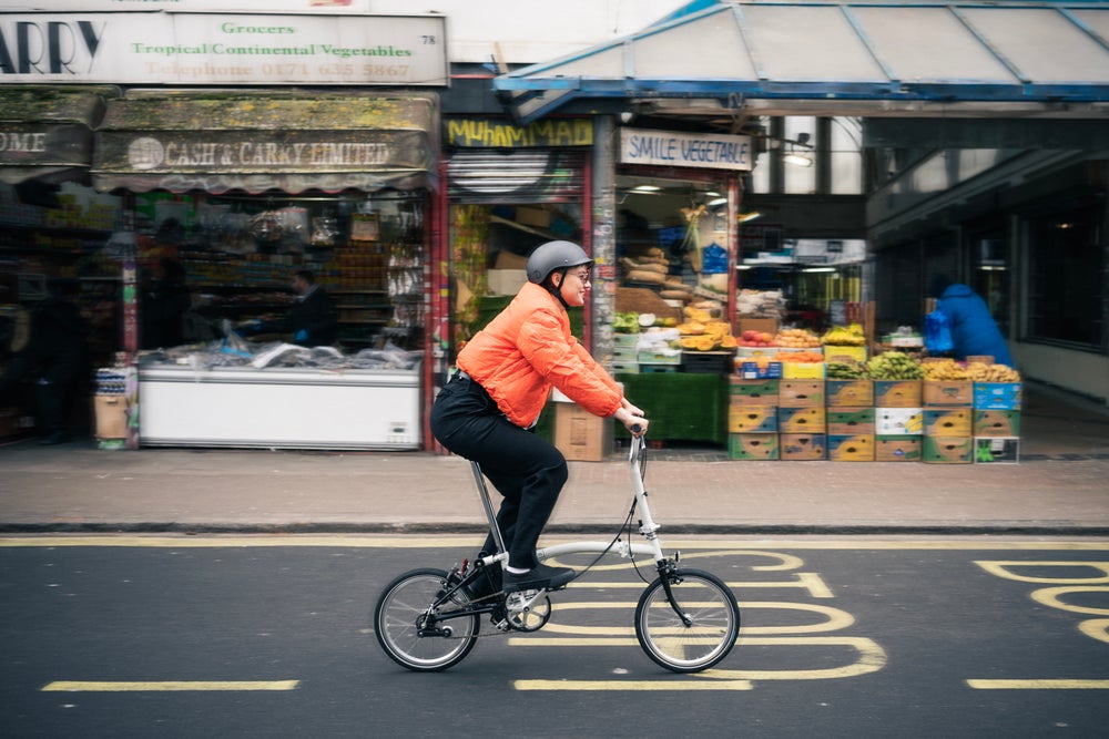 Une image de mode de vie montrant un vélo pliant Brompton A Line contre un mur bleu