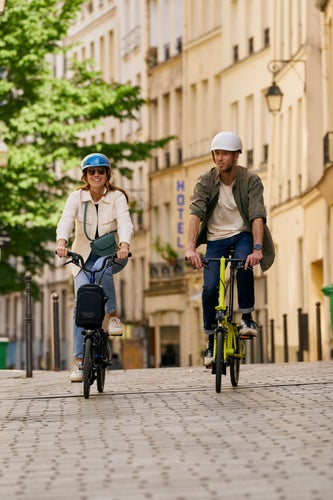 two people riding brompton electric bikes in paris