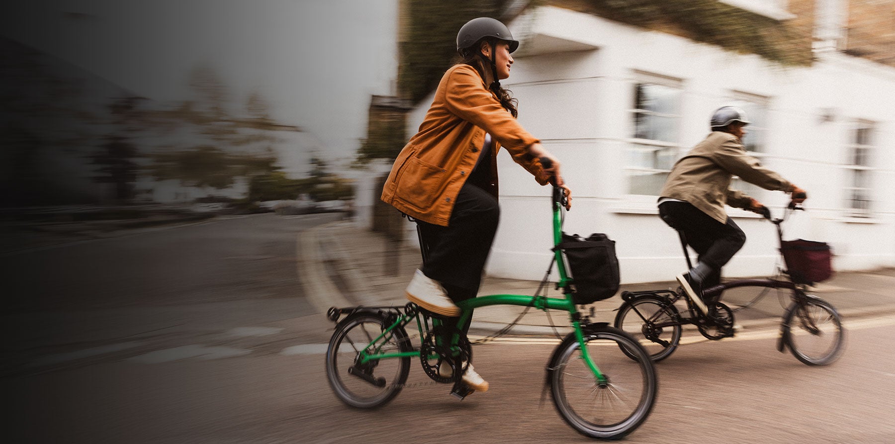 Zwei Leute, die mit Brompton-Fahrrädern auf der Straße unterwegs sind