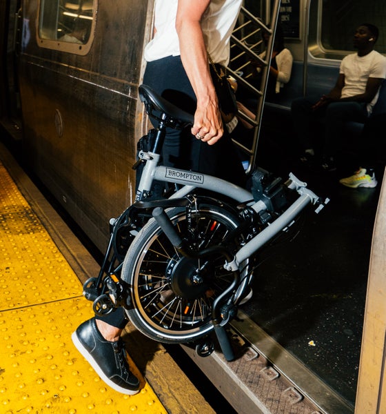 person wheeling a dune sand folded brompton electric bike on train platform