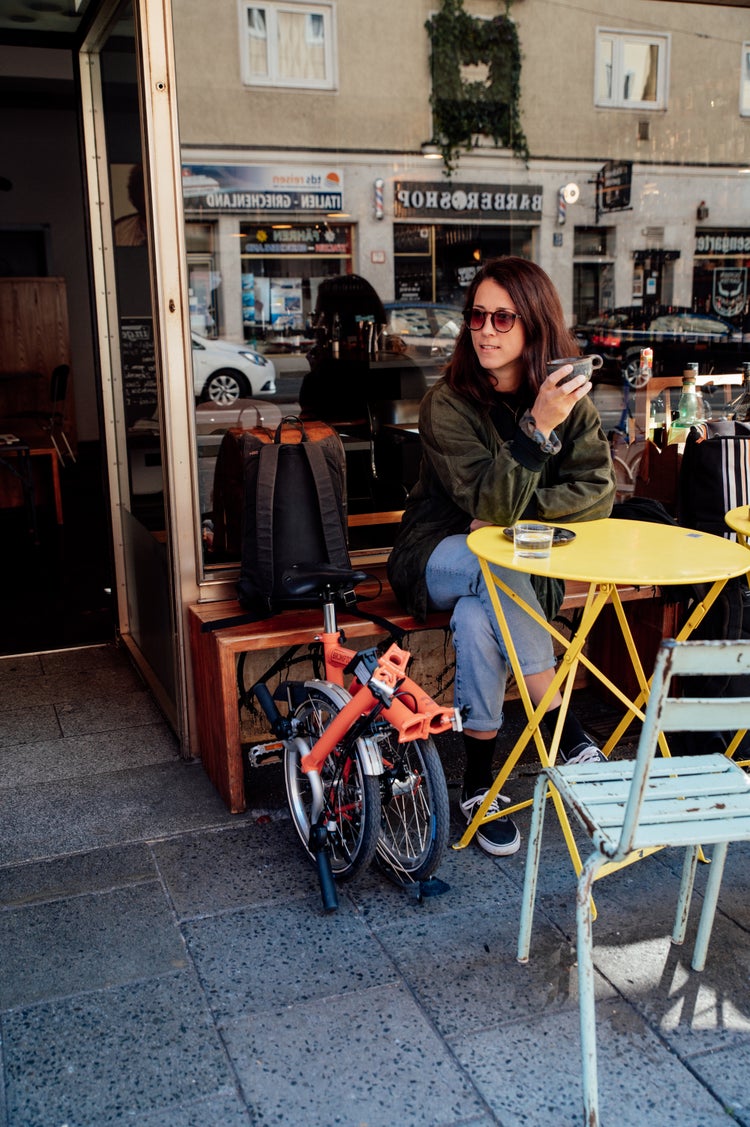 Woman outside cafe with Brompton C Line folded by her side