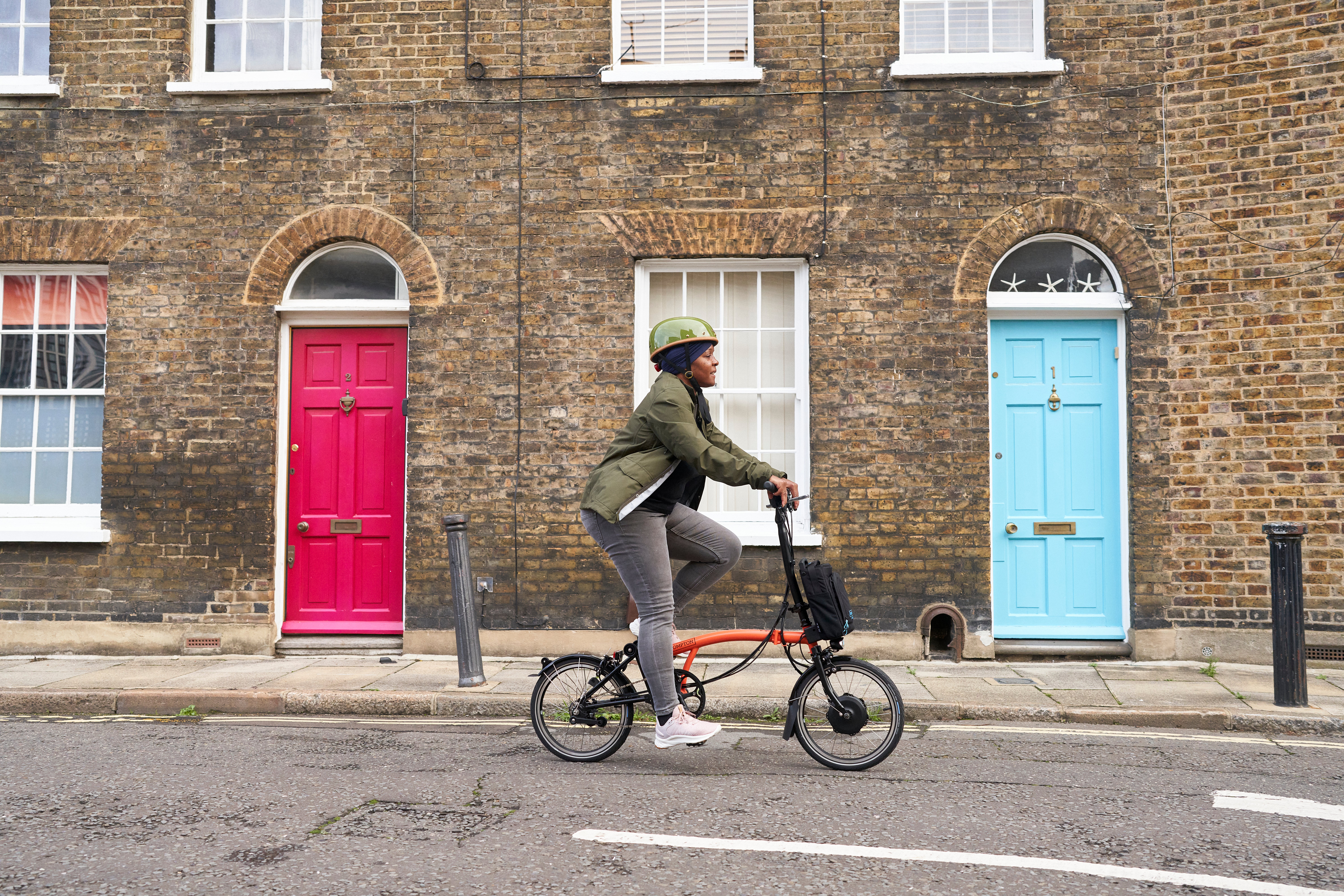 Person riding a fire coral Brompton bike down a London street