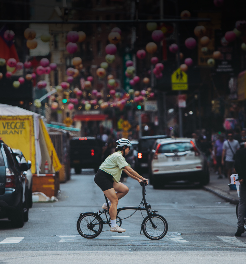 A woman riding a Brompton P Line folding bike through the streets of NYC