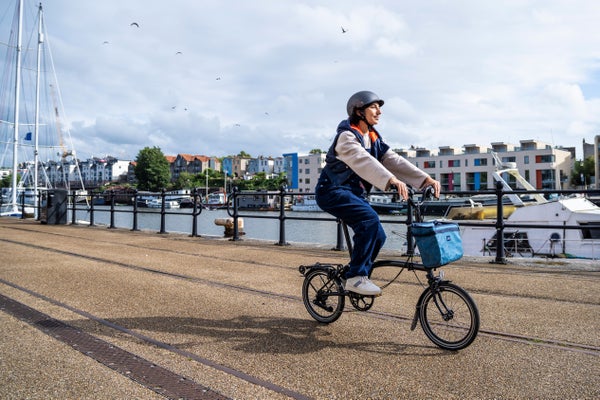 Person riding a Brompton by a river dock