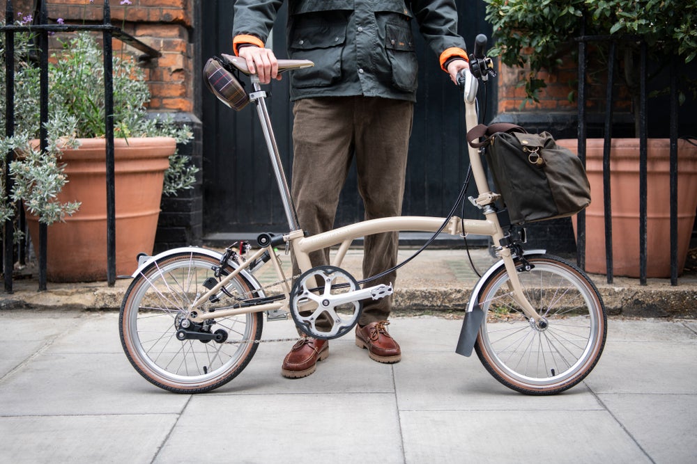 Two people wearing the Barbour x Brompton collection on special edition Barbour x Brompton bikes