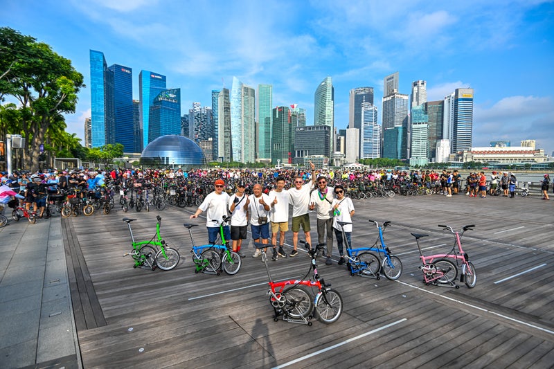 brompton team with their bikes in front of singapore skyline