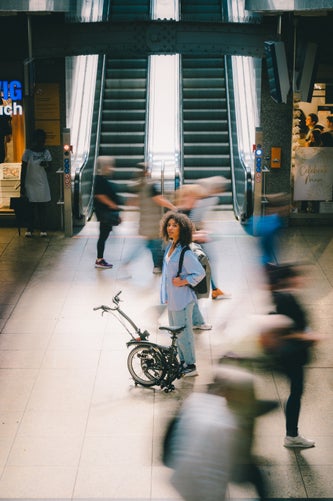 person wheeling brompton bike through station