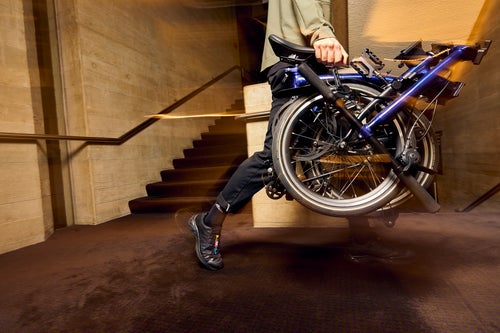 person carrying a brompton electric p line in bolt blue