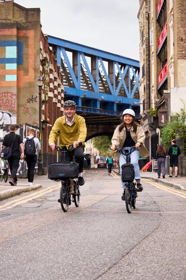 Two happy people riding Brompton Electrics through London