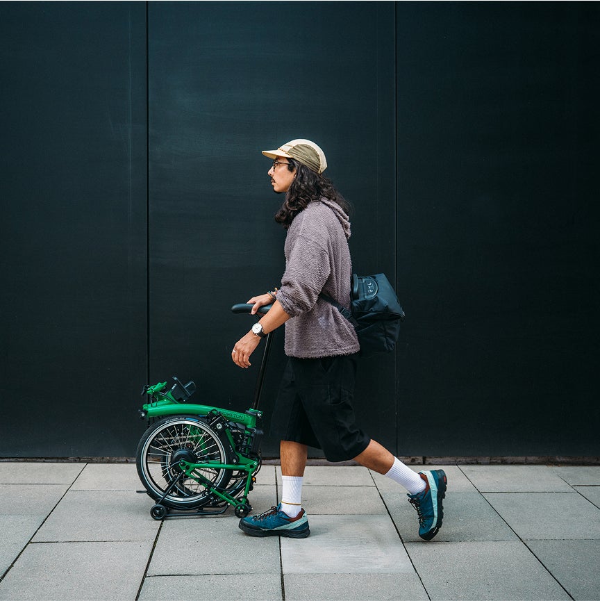 Un mec pousse un Brompton Electric C Line en mode SuperRoll+.