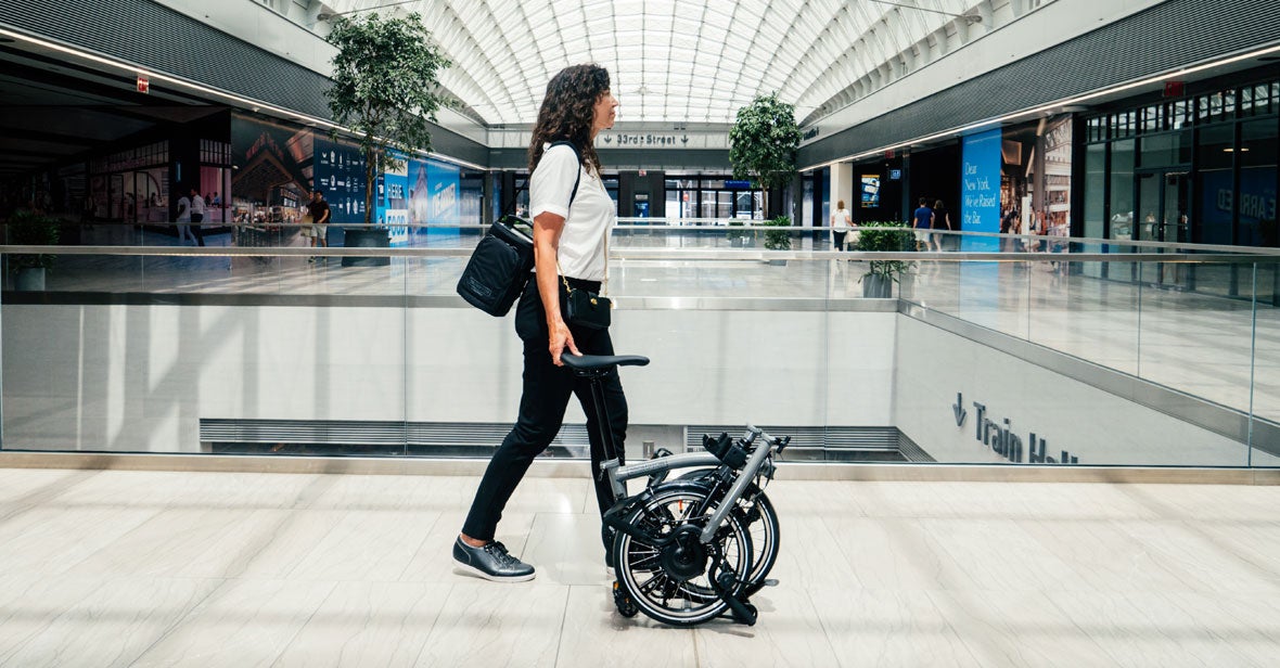 Woman pushing folded Brompton bike