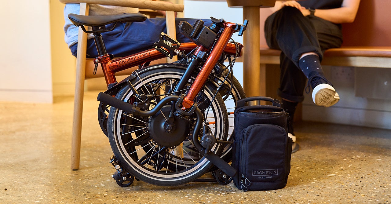 Woman sat on step with folded electric Brompton