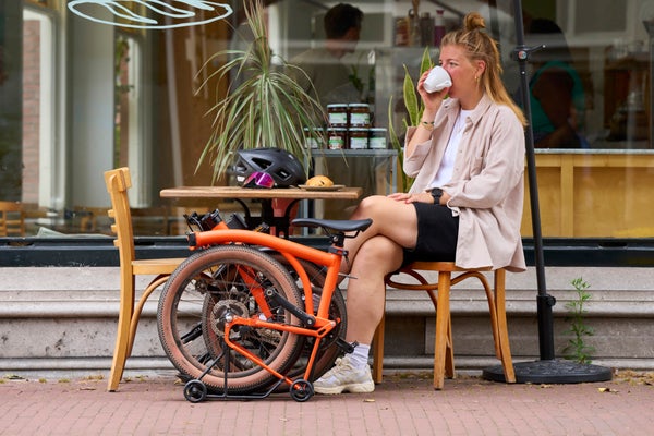 Person sat outside café with a folded Brompton bike