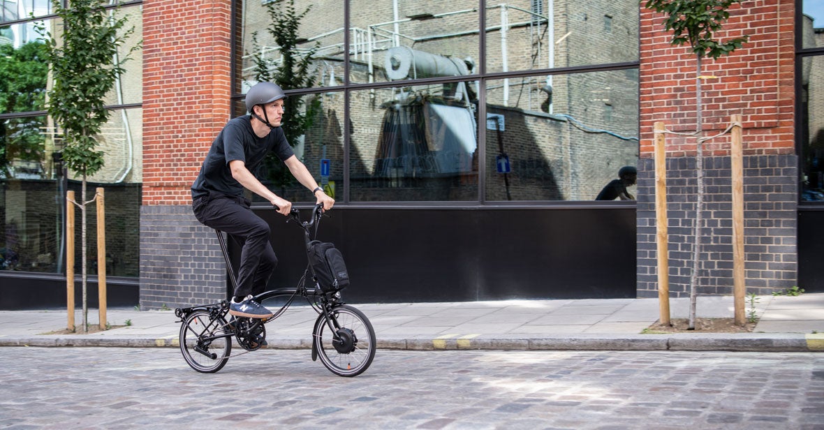 Uomo in sella alla bicicletta elettrica Brompton