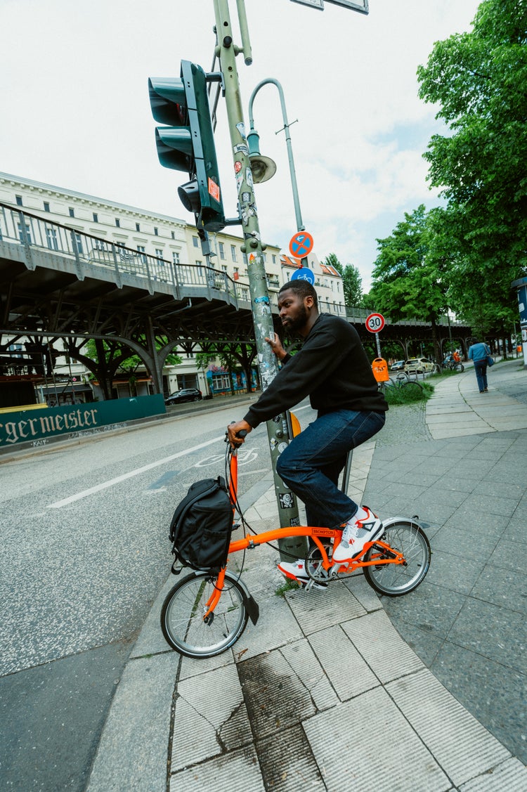 person riding brompton fire coral across a road in berlin