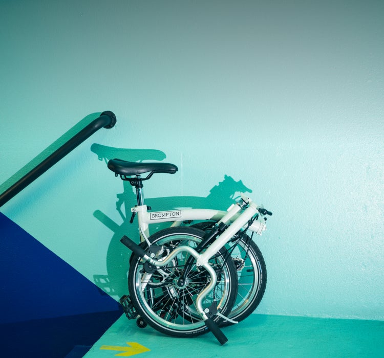 A folded Brompton A Line against a teal and navy wall