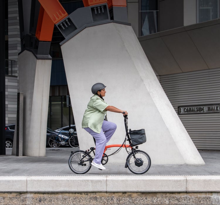 A woman riding a Brompton Electric C Line through the streets of London