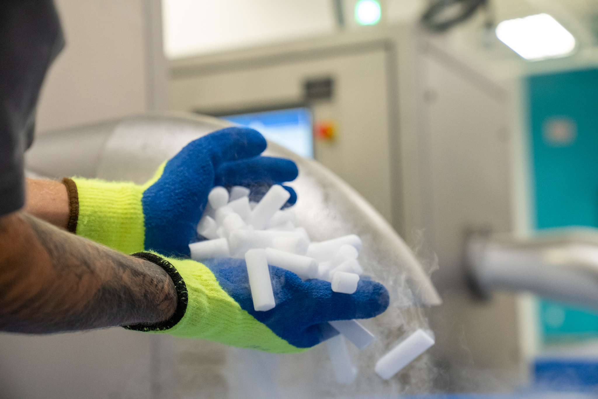 Pastilles de glace carbonique tenues dans une main gantée, média utilisé pour le nettoyage cryogénique.