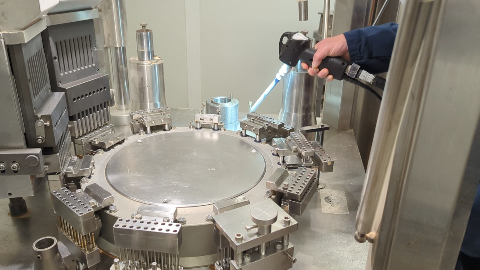 Opérateur projetant de la glace carbonique avec un pistolet Cold Jet sur l'outillage d'une machine de production.