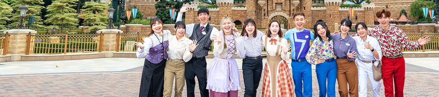 group of colleagues in colorful uniforms and costumes standing in front of a castle