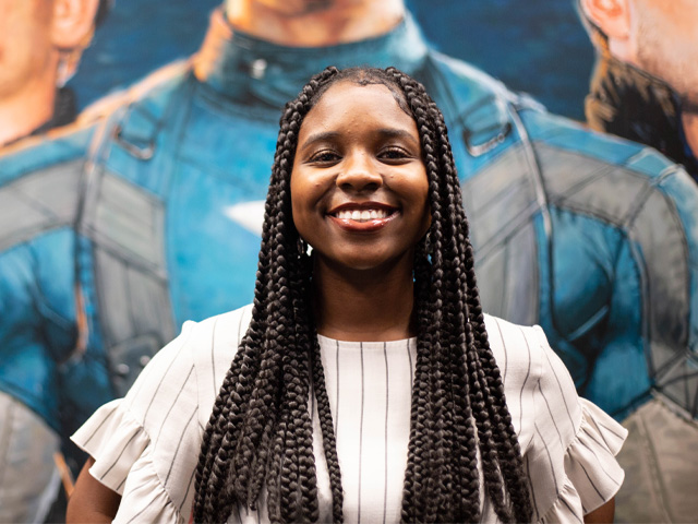 n Smiling woman with braids against a superhero mural
