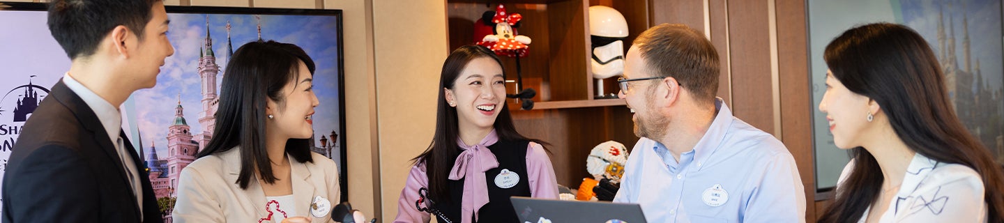 group of employees in business attire, smiling and conversing with each other