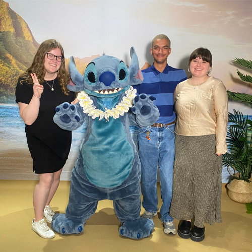 Disney UK Intern Callum, wearing a black polo and smiling with Daisy Duck