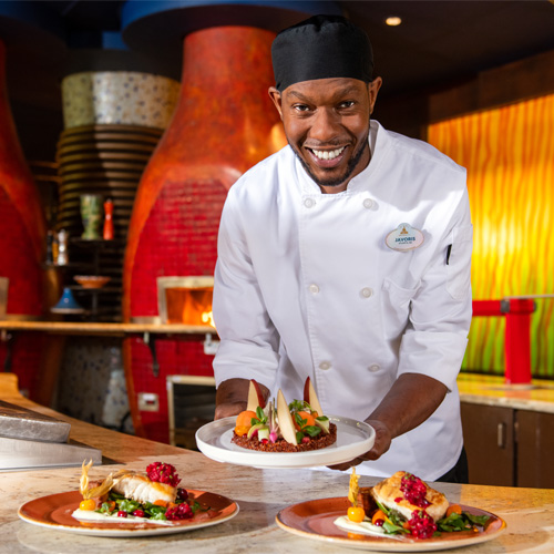 A chef presenting dishes of prepared food