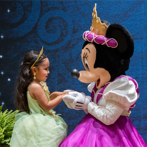 Child in a princess costume interacting with Minnie Mouse dressed in royal attire during a character meet-and-greet