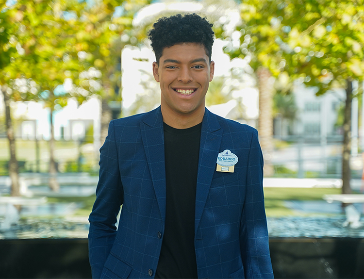 Disney intern Eduardo smiling wearing a blue blazer and black shirt