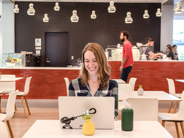 Smiling woman working on a laptop in a modern cafe