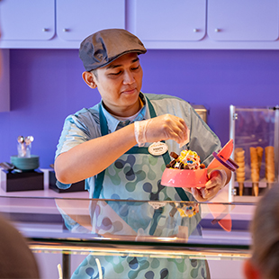 male DCL employee sprinkling toppings onto a bowl of icecream