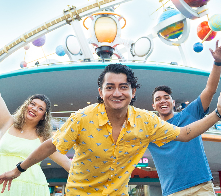 three young people celebrating at a Disney park's Tomorrowland attraction