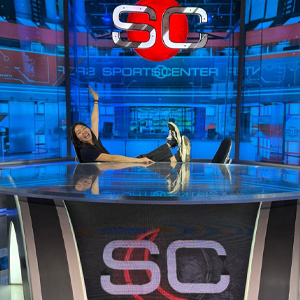 Person posing on the SportsCenter studio desk in front of the SportsCenter set
