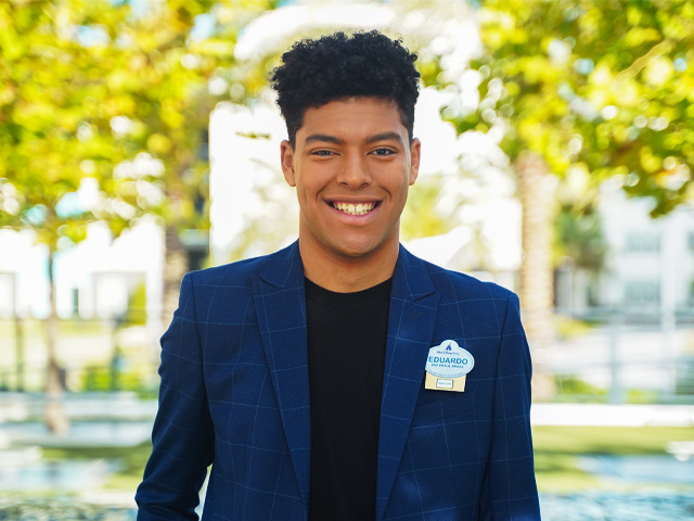 A smiling Disney Programs participant in a blue blazer in an outdoor setting