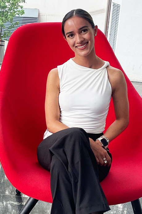 The Walt Disney Company Mexico intern Ana wearing a white shirt and black pants smiling while sitting on a bright red chair