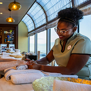 female spa employee in uniform, smiling and folding towels