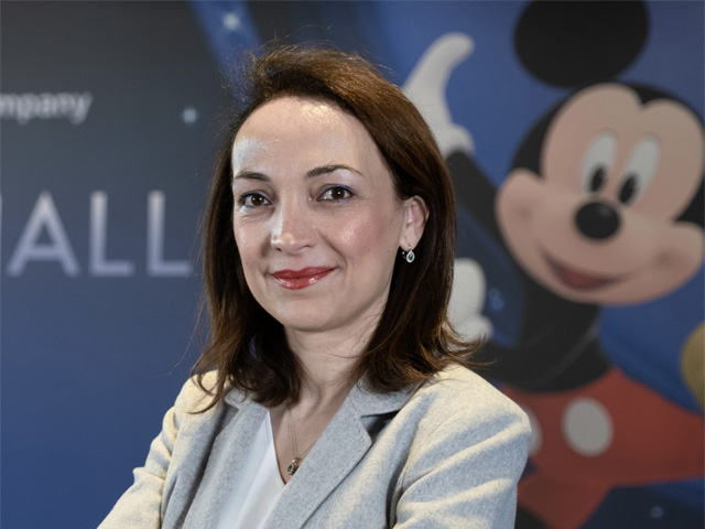 A professional woman with Mickey Mouse in the background