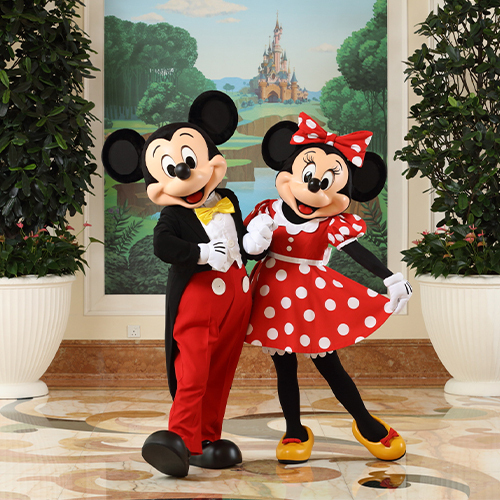 Mickey Mouse and Minnie Mouse standing in front of a poster at Hong Kong Disneyland