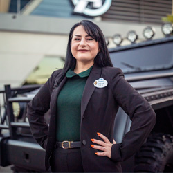 A woman poses confidently in front of an Avengers logo and vehicle