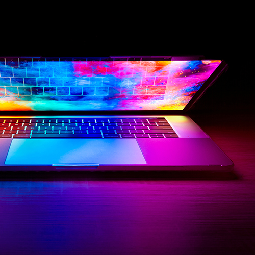 laptop with a colorful screen half closed in a dark room