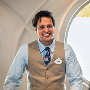 male employee with a friendly smile, wearing a uniform and name tag