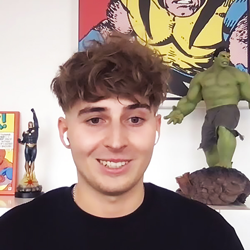 Disney UK Intern Filip, wearing a black shirt and smiling in front of Marvel wall decorations