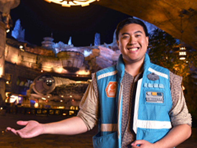 A smiling cast member in a themed vest at Star Wars: Galaxy's Edge