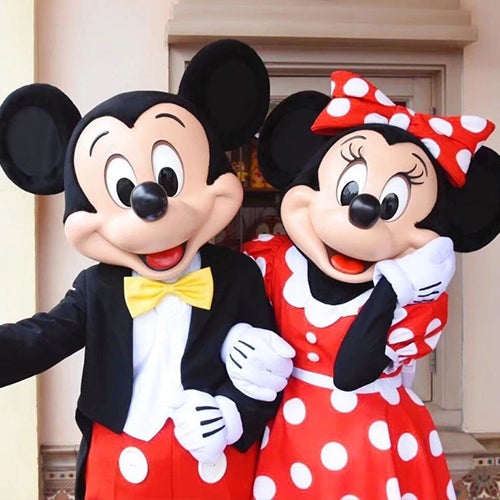 two Disney cast members dressed as Mickey and Minnie Mouse, linking arms
