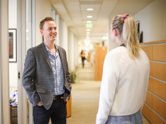 Two colleagues chatting in an office hallway