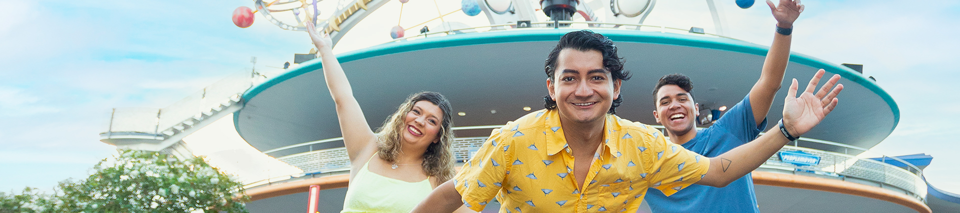 three young people celebrating at a Disney park's Tomorrowland attraction