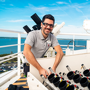 male technician in uniform and goggles, smiling as he inspects fireworks set up to launch