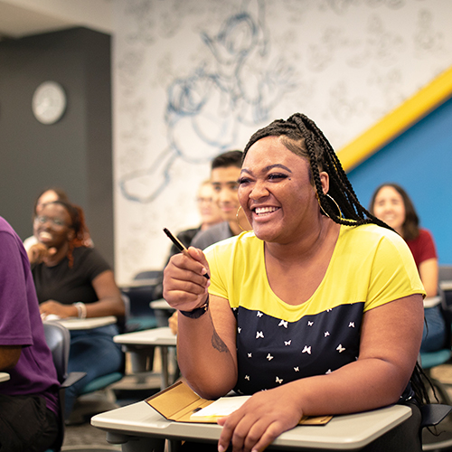 Young black female college student sitting in a classroom, laughing