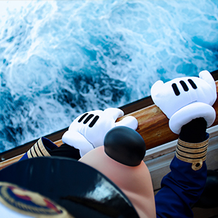 employee wearing a Mickey costume and looking over the bow of a Disney Cruise Line ship